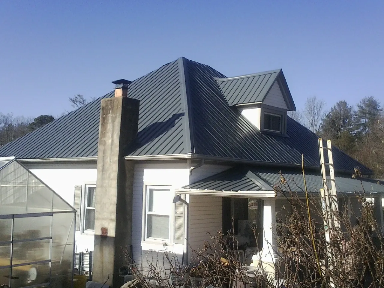 Dark blue standing seam metal roof on a white farmhouse with dormer — Slate & Tile Roof Repair by Roofing Brothers in Manteca