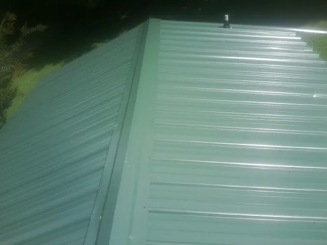 New green metal panels meeting at the ridge of a roof — Flat Roof Repair work by our crew in Manteca