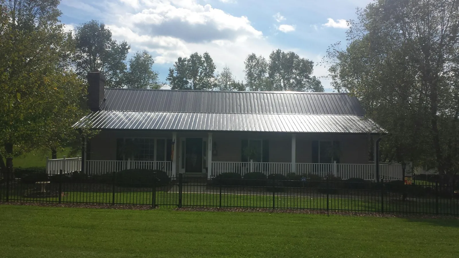 Gray metal roof on a brick ranch with a full width front porch — Gutter Guard Installation work by our crew in Manteca