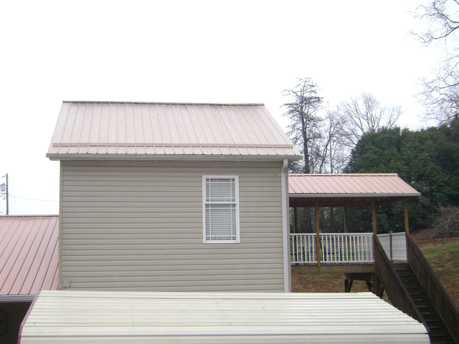 Tan metal roofs on a two story addition and attached porch, from a Roof Replacement job in Manteca