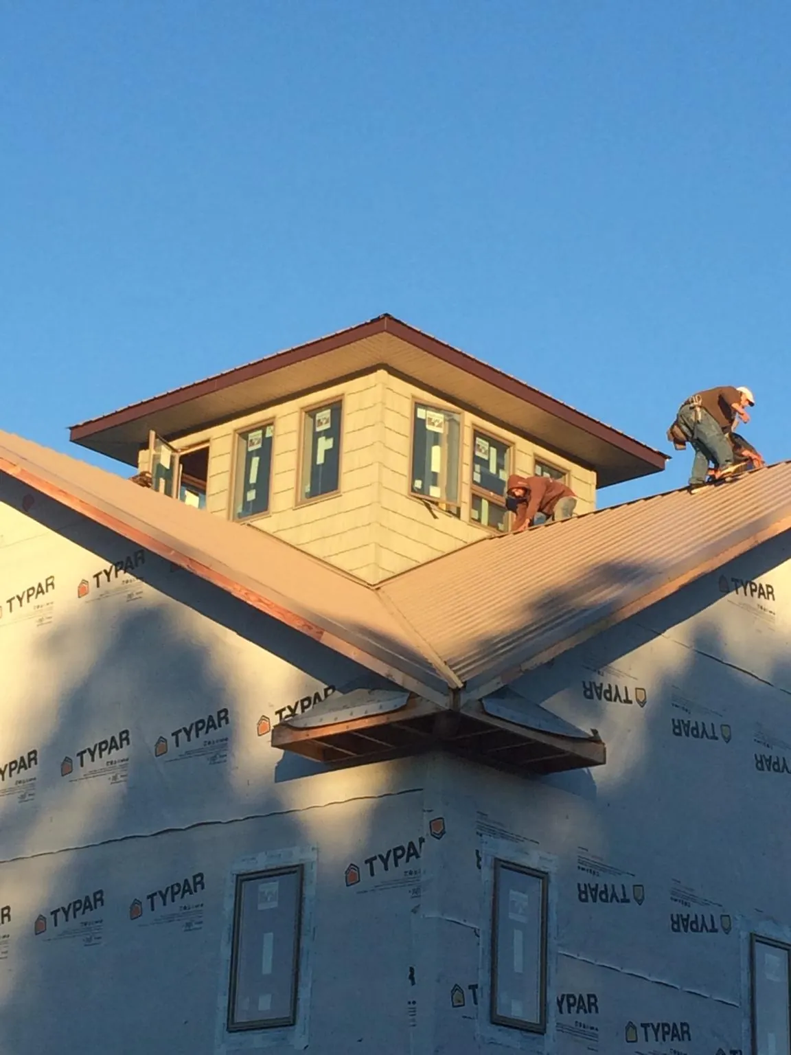 Roofers working around a rooftop cupola on a new metal roof at sunset — Roof Waterproofing in Manteca by Roofing Brothers